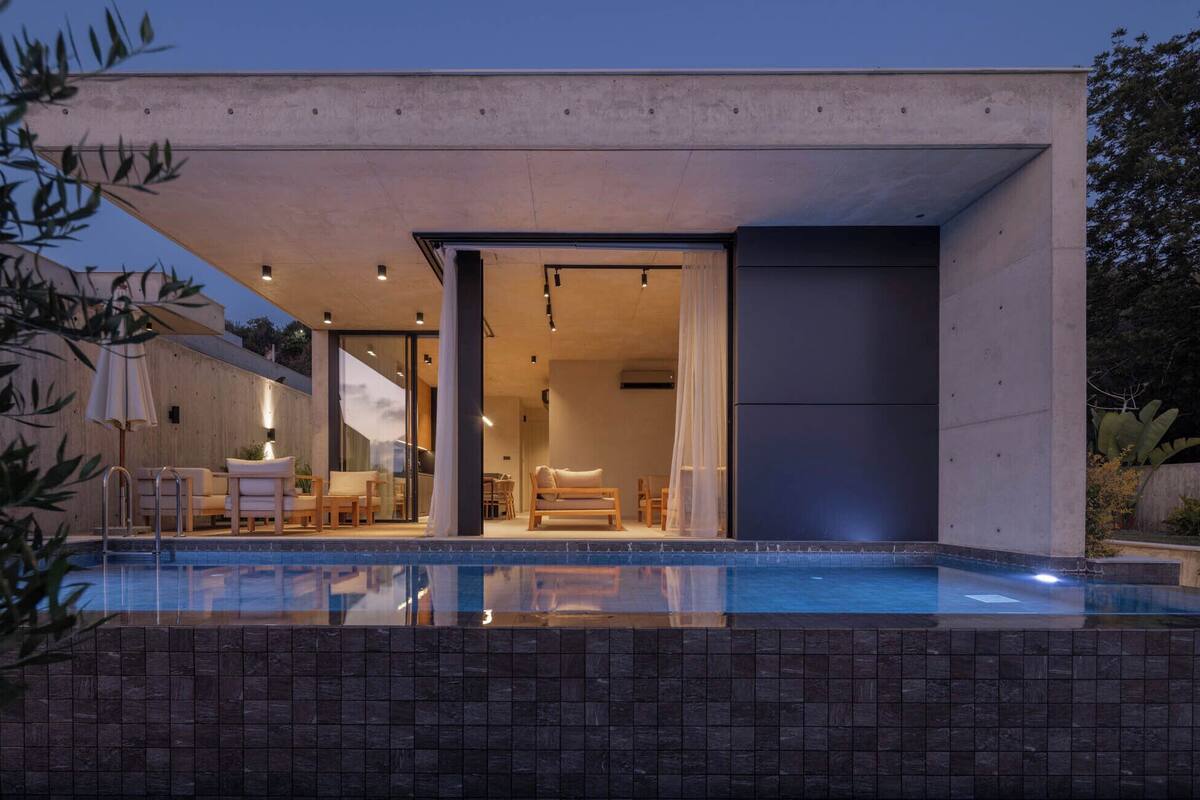 A modern house with a swimming pool, outdoor seating, and a large sliding door leading to the interior.