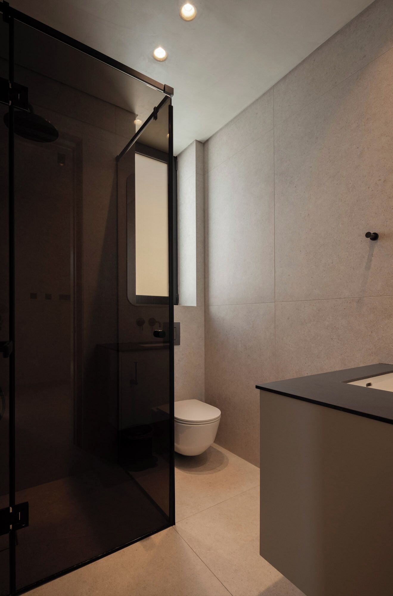 Un baño moderno con cabina de ducha de vidrio, inodoro y lavabo con espejo.