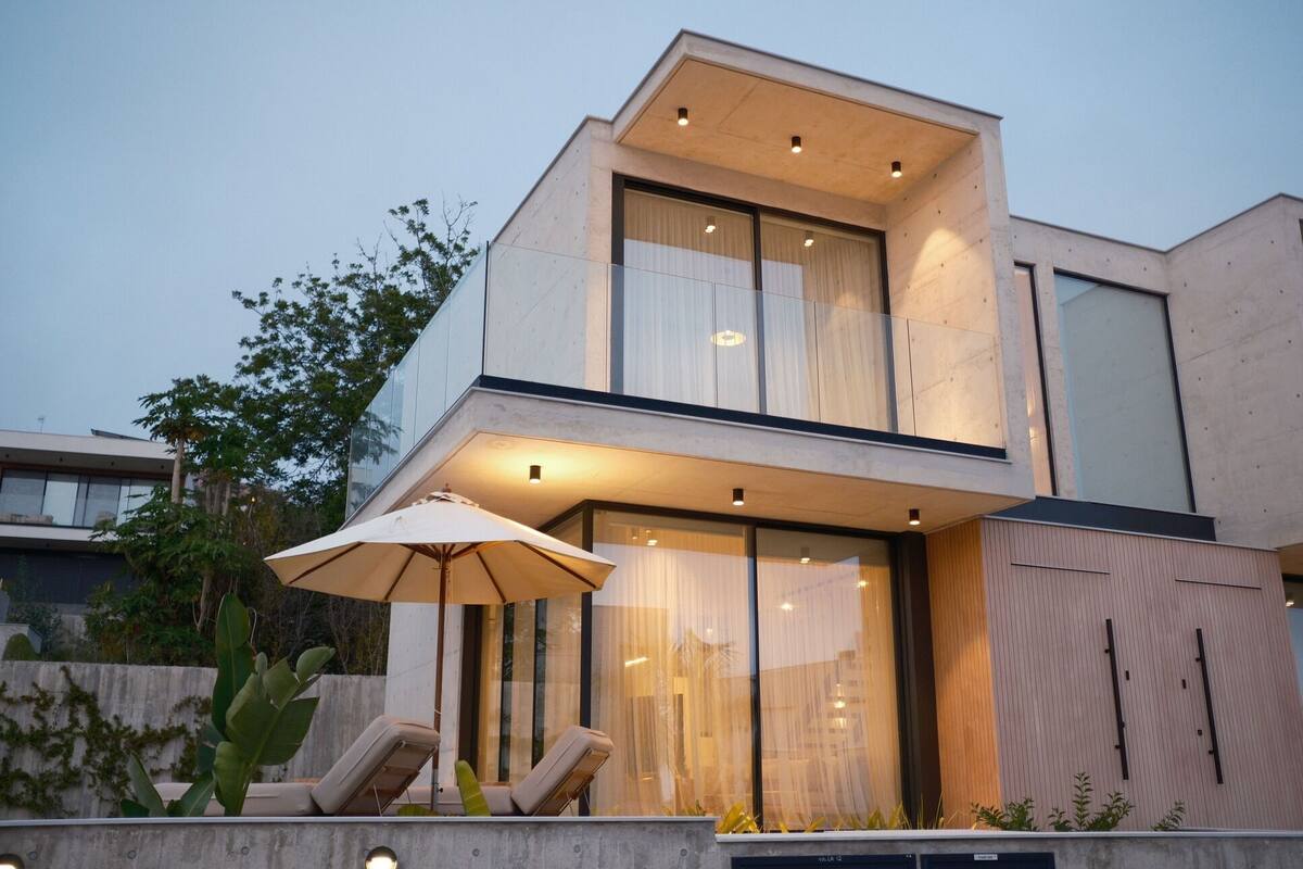 A modern two-story house with large windows and a balcony.