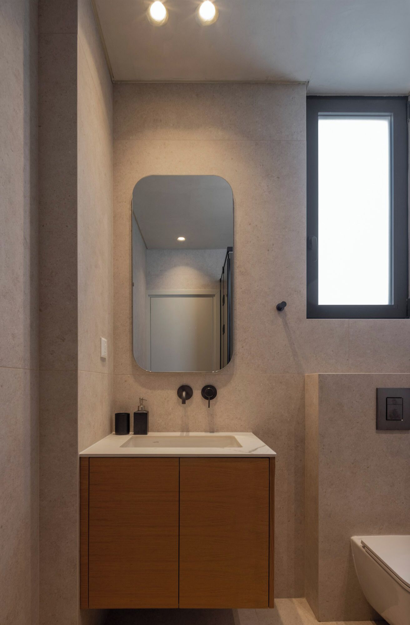 Un baño moderno con tocador de madera, un espejo grande y una ventana que proporciona luz natural.