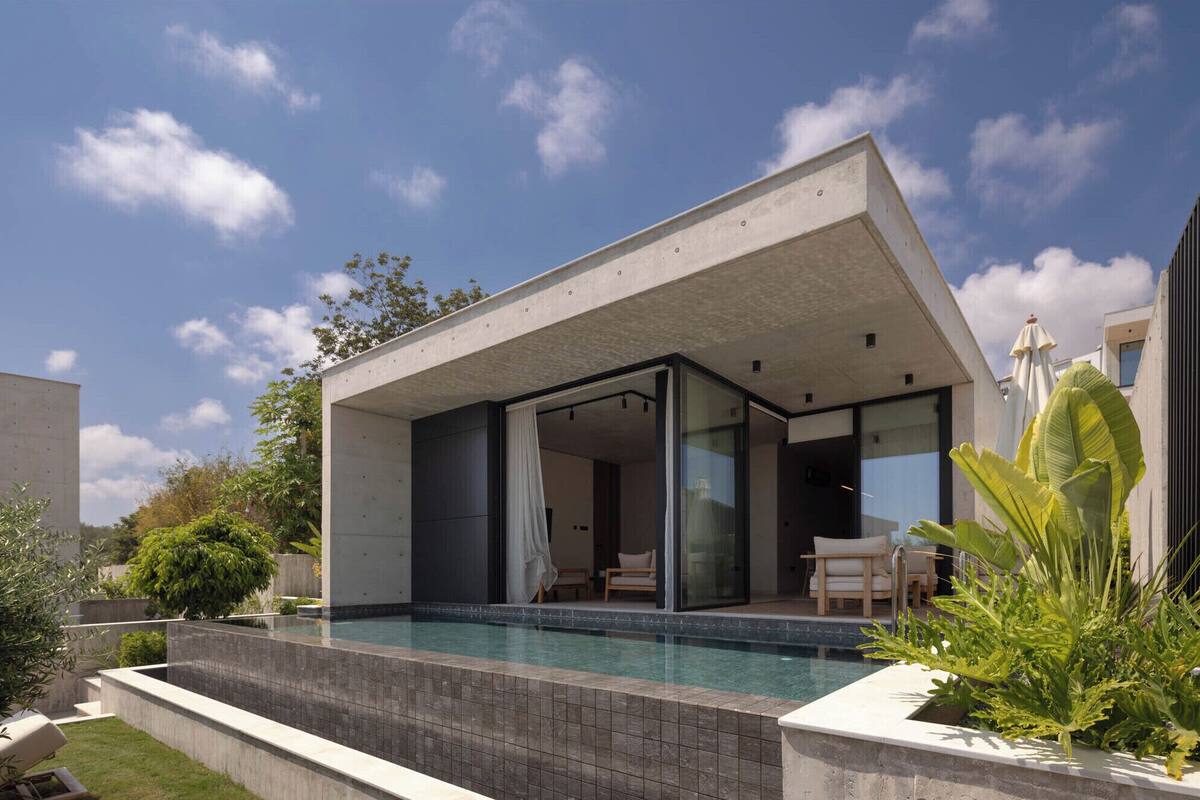 A modern house with a swimming pool, glass doors, and outdoor seating.