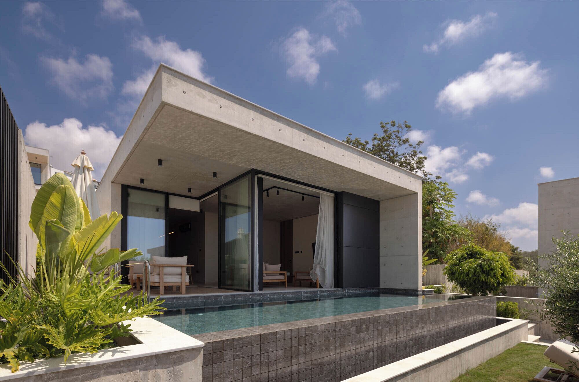 A modern house with a swimming pool, large windows, and a patio area.