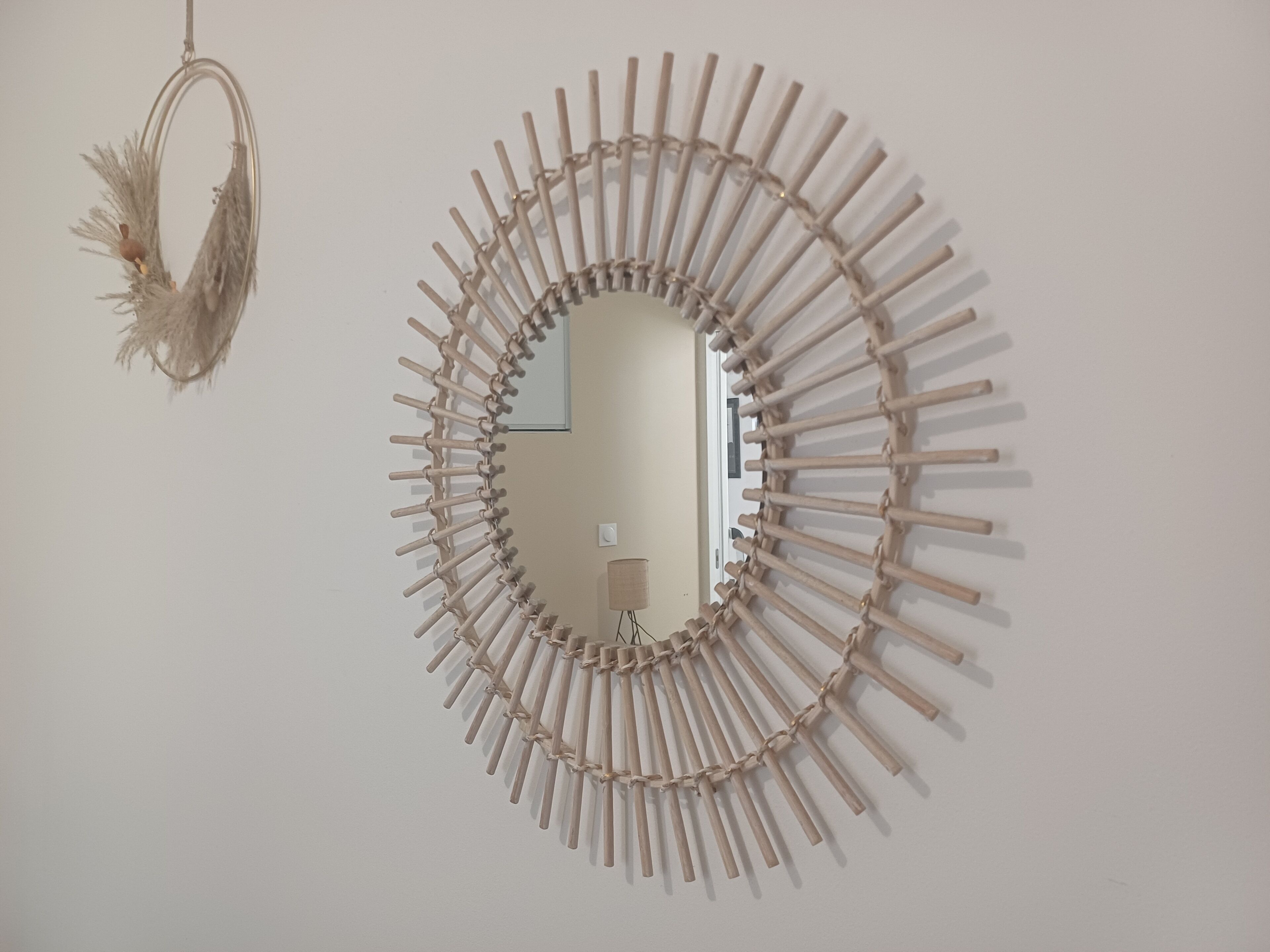 Un miroir rond, encadré de bois, est accroché à un mur uni.