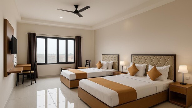 A hotel room with two beds, a desk, a chair, a TV, and a ceiling fan. - TGR Hotel (Mundra)