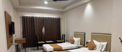 A hotel room with two beds, a desk, a chair, and a TV.