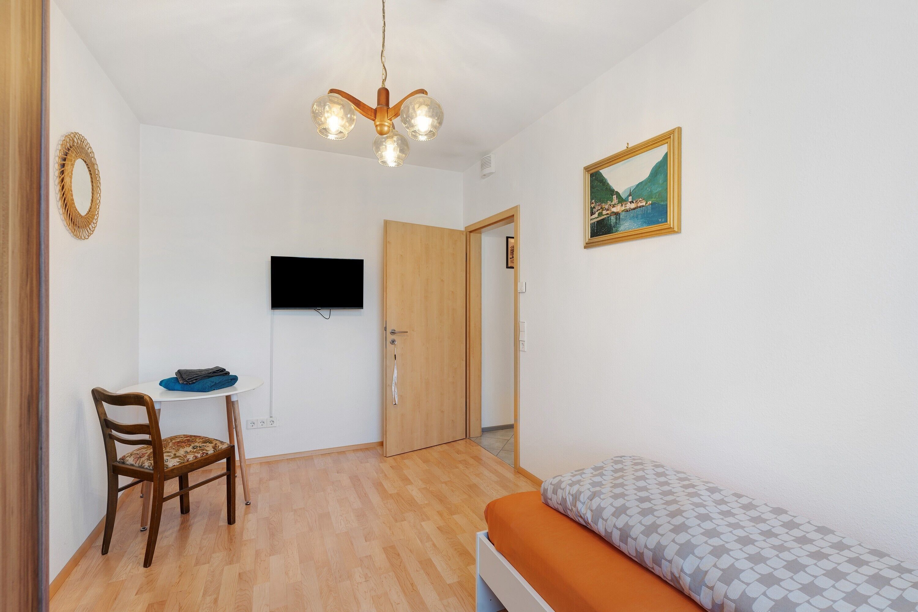 Una stanza con un letto, una scrivania con una sedia, un televisore e una porta.