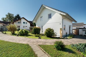A residential house with a paved driveway, a small garden, and a clear blue sky. - Holiday Home 'Langer' with Mountain View, Private Terrace and Wi-Fi (Oberkirch)