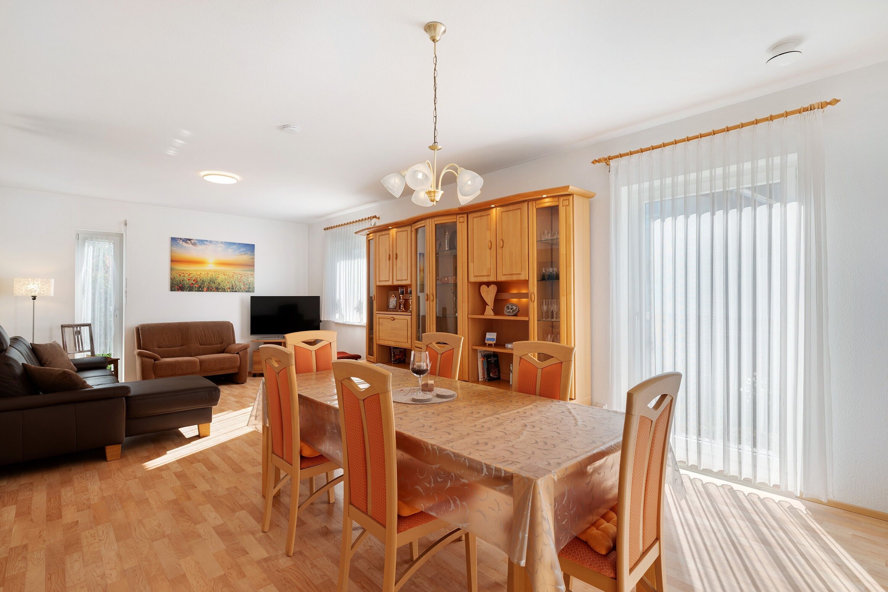 Ein Wohnzimmer mit Sofa, Fernseher und Essbereich mit Tisch und Stühlen.