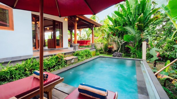 A pool area with a red umbrella, wooden deck, and lounge chairs. - Soma Uma Dhara private pool villa designed for soulful rest and natural luxury. (Bali)