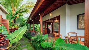 A covered outdoor area with a stone pathway, wooden furniture, and tropical plants. - Soma Uma Dhara private pool villa designed for soulful rest and natural luxury. (Bali)
