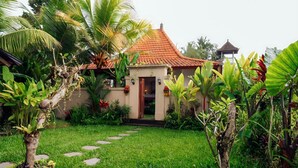 A house with a tiled roof, a garden with a stone pathway, and tropical plants. - Soma Uma Dhara private pool villa designed for soulful rest and natural luxury. (Bali)