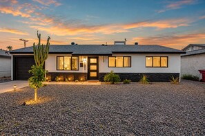A modern two-story house with a stone facade, a front porch, and a well-maintained gravel driveway.