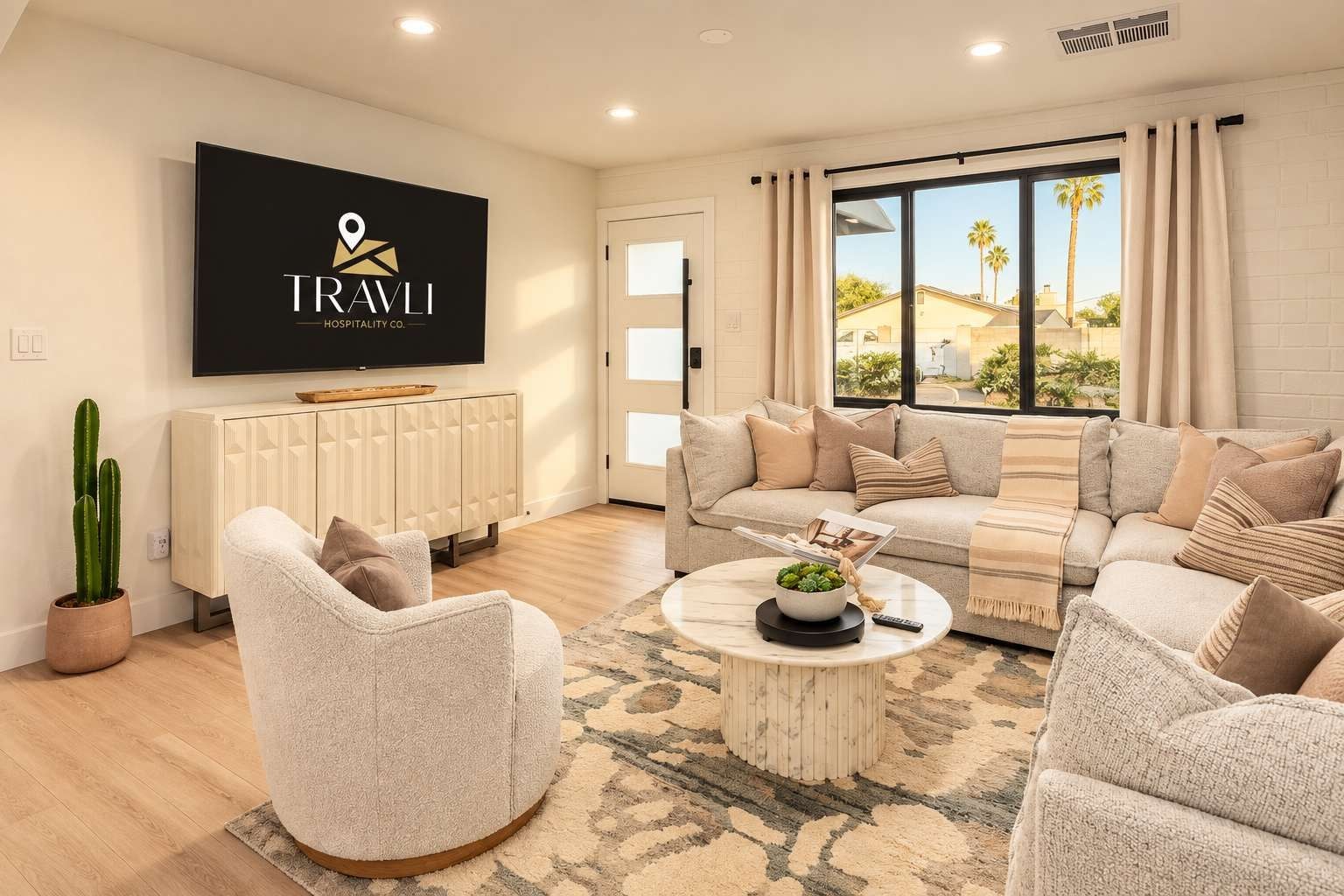A modern living room with a flat-screen TV, a sofa set, a coffee table, and a cactus plant.