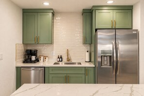 A kitchen with green cabinets, a stainless steel refrigerator, a coffee maker, and a dishwasher. - Casa Del Rey Old Town Retreat | Pool & Casita (Scottsdale)