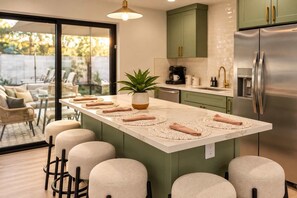A modern kitchen with a central island, green cabinets, and a stainless steel refrigerator. - Casa Del Rey Old Town Retreat | Pool & Casita (Scottsdale)