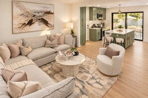 A modern living room with a sectional sofa, a round coffee table, and a dining area with a bar. - Casa Del Rey Old Town Retreat | Pool & Casita (Scottsdale)