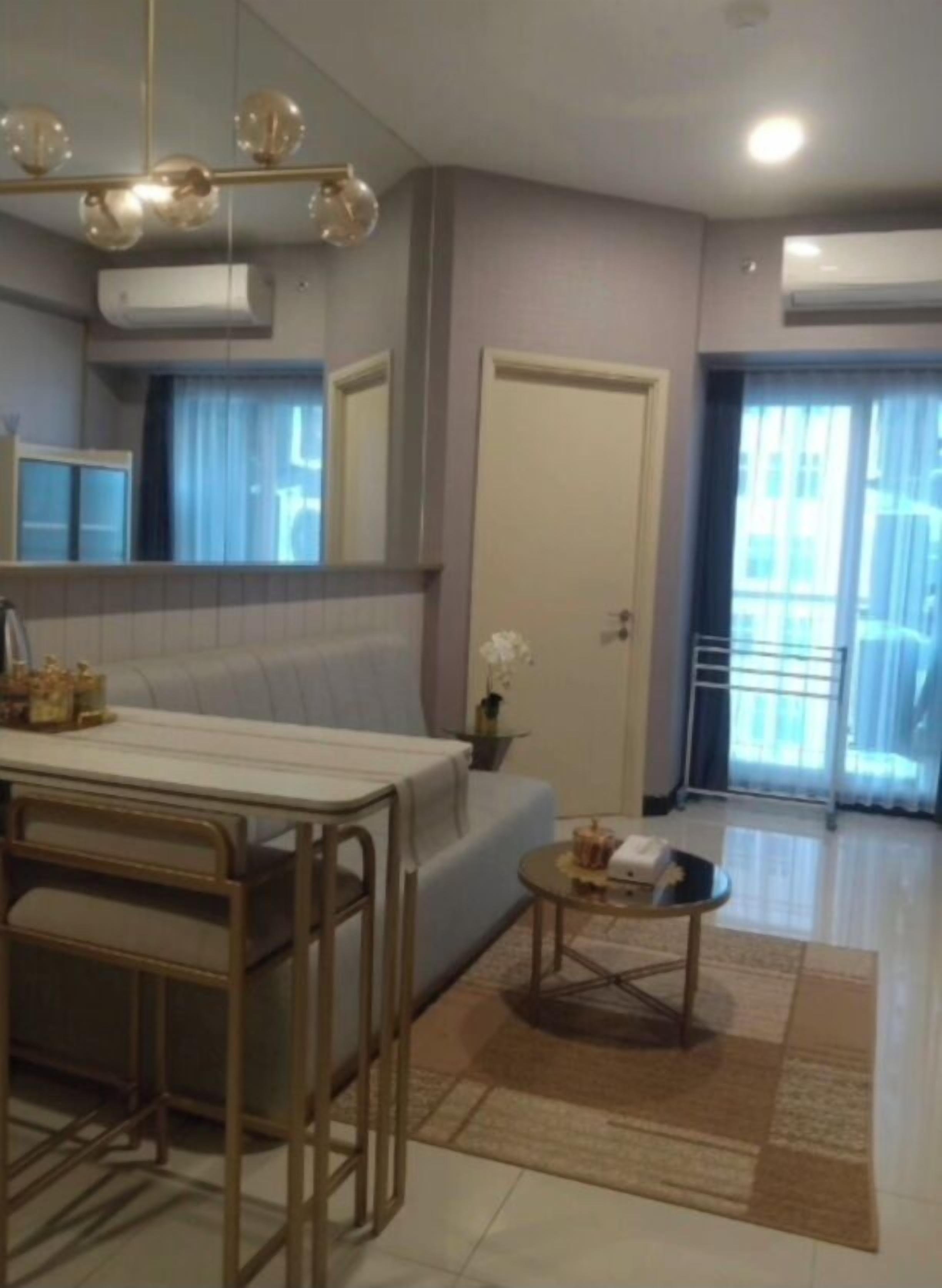 A modern living room with a sofa, a coffee table, a dining area with a table and chairs, and a large mirror.