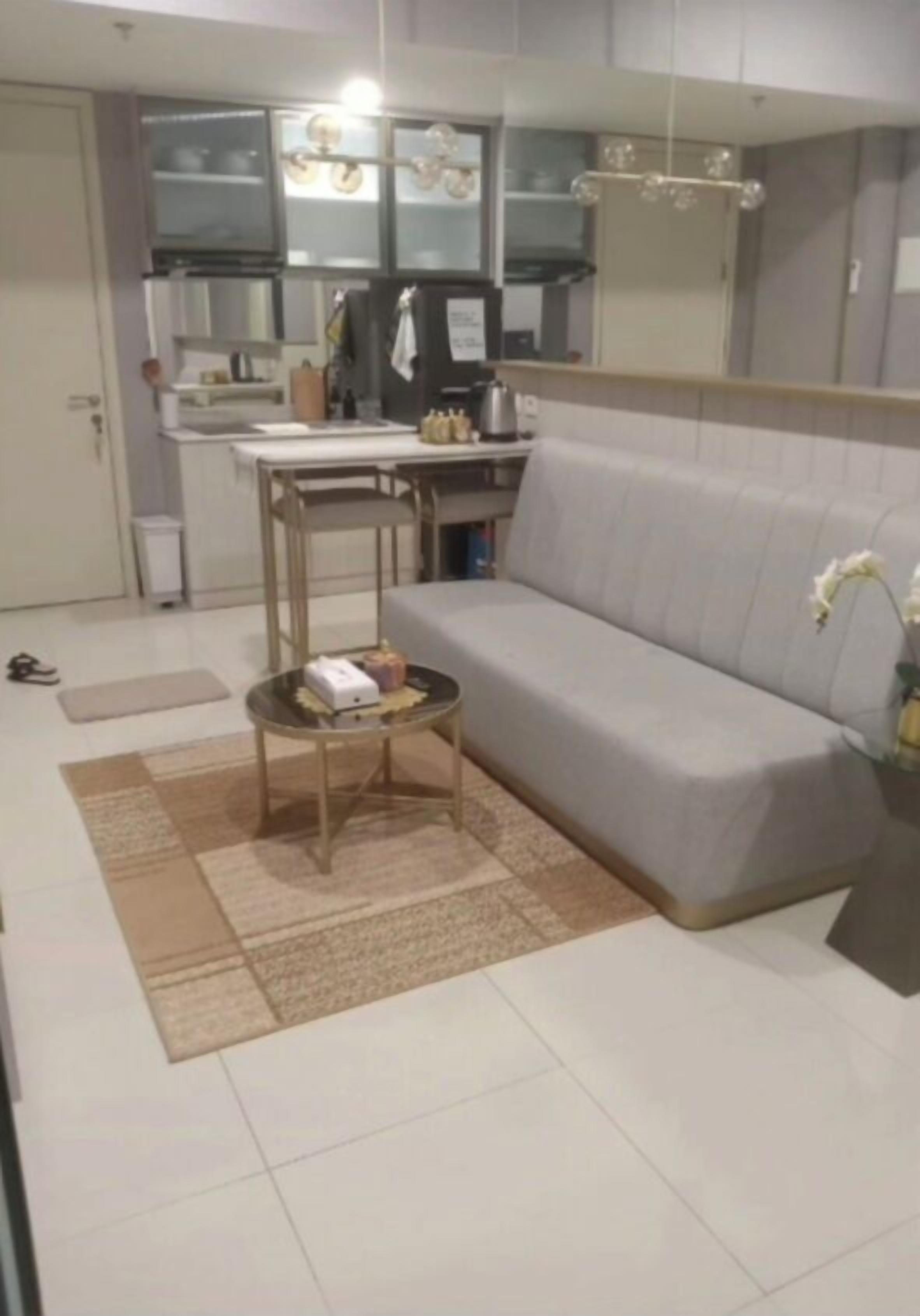 A living room with a sofa, a small round table, and a kitchen area in the background.