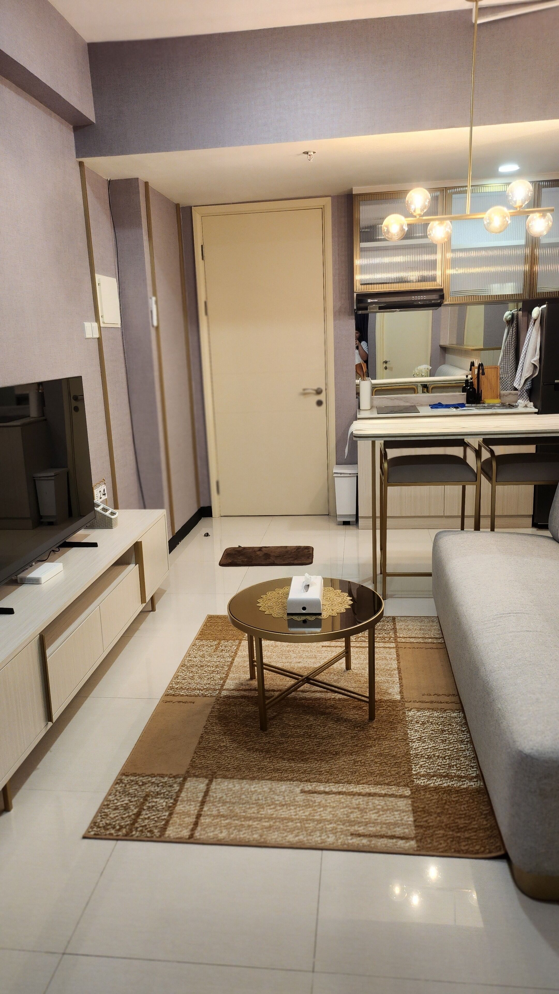 A modern living room with a sofa, a coffee table, a TV, and a kitchen area with a dining table and chairs.