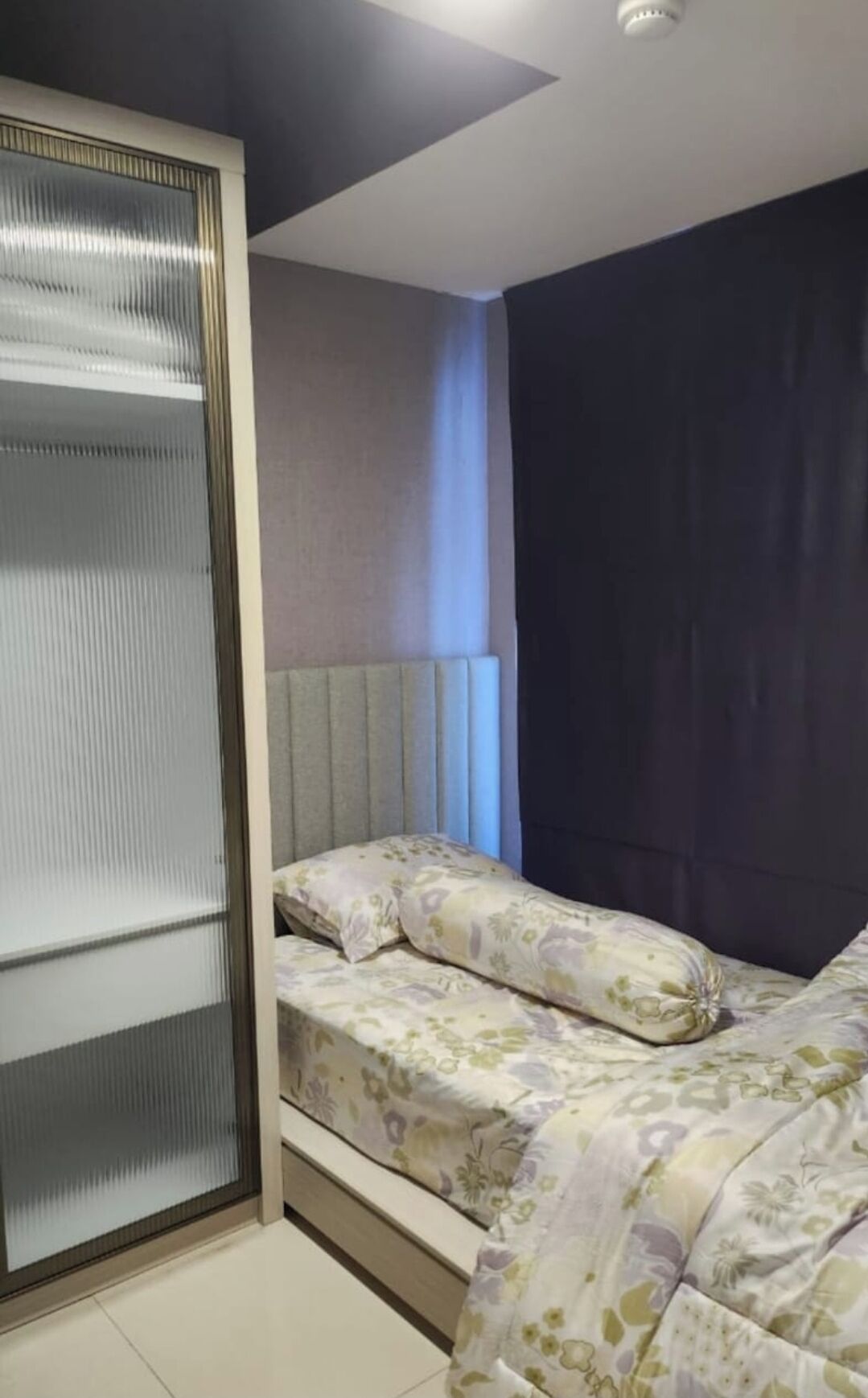 Une chambre à coucher avec un lit, une armoire et une fenêtre avec des rideaux.