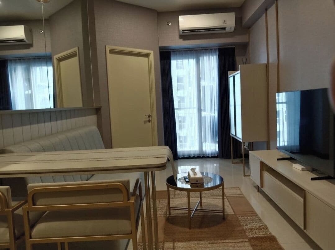 Une chambre d’hôtel avec un lit, une petite table sur laquelle se trouve une boîte de mouchoirs, un téléviseur posé sur un meuble et une fenêtre avec des rideaux.