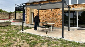 Un edificio moderno con fachada de piedra y un patio cubierto con un banco.