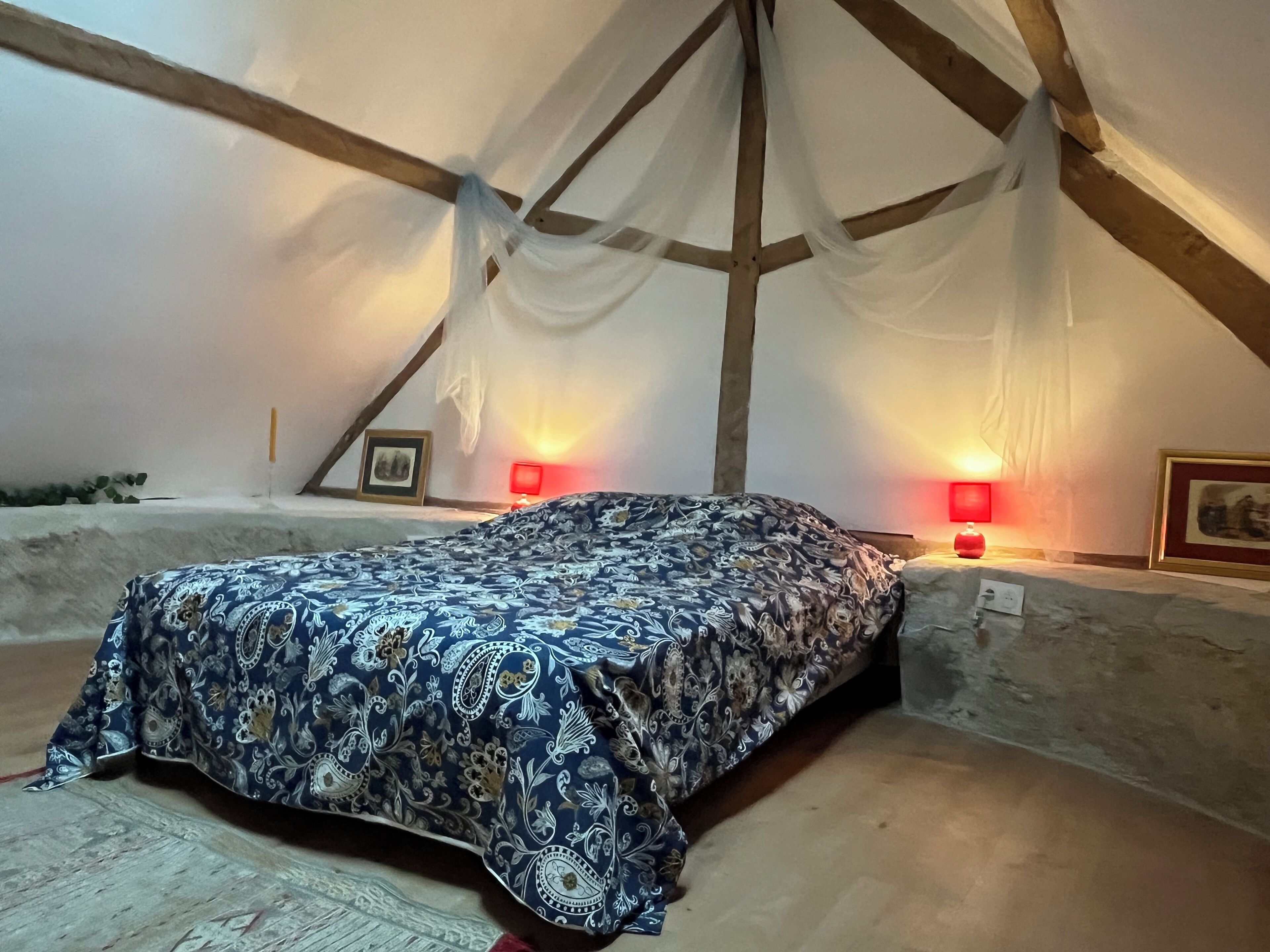 Ein Schlafzimmer mit einem Bett, zwei Nachttischlampen und einem gerahmten Bild an der Wand.
