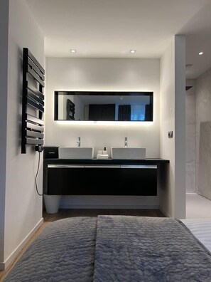 Une salle de bain moderne avec un grand miroir, deux lavabos et un meuble-lavabo noir.