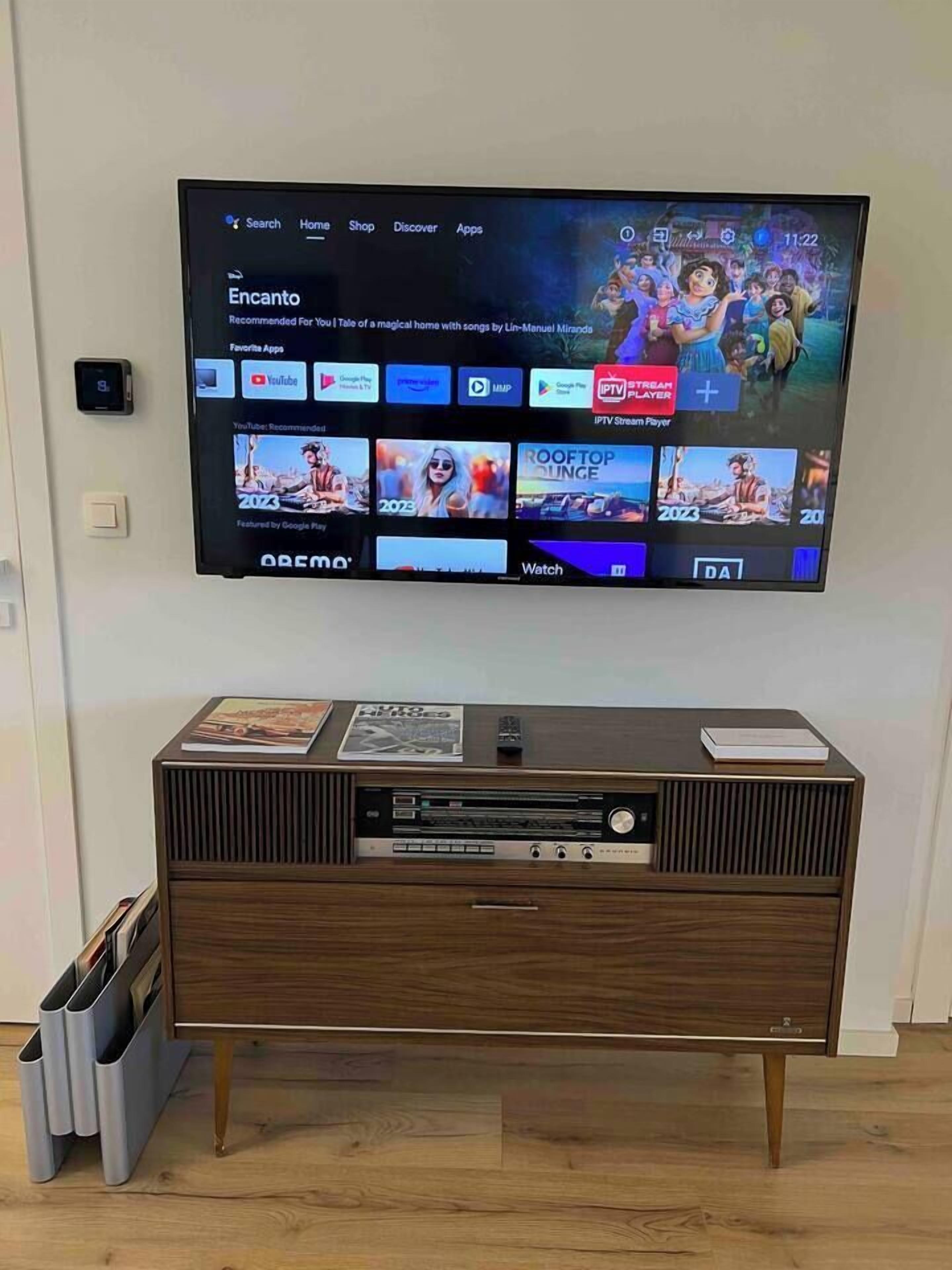 A television mounted on a wall with a wooden entertainment unit below it.