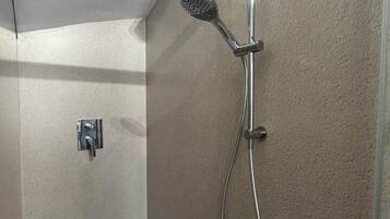 Een douche met een handdouche en een douchekop aan de muur.