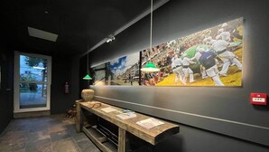 Een gang met een bankje, een kunstwerk aan de muur en een brandblusser.