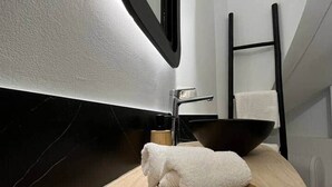 A bathroom with a wooden vanity, a black sink, a mirror, and a towel on a wooden tray. - Urban Les Chartriers (Mons)
