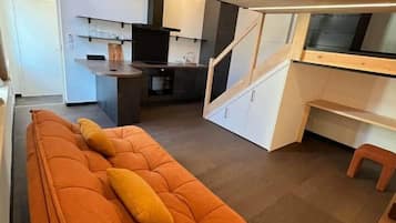 Een modern interieur met een bank, keuken en eethoek.