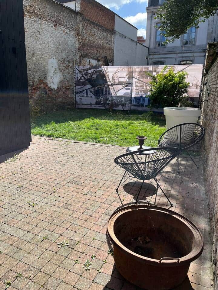 Eine Terrasse mit Pflasterboden, zwei Metallstühlen und einem großen Terrakottatopf.