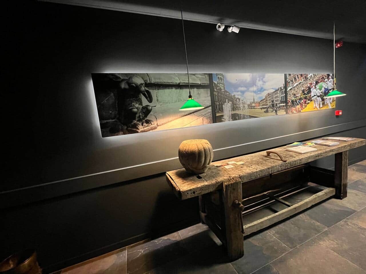 Un banc agrémenté d’un objet décoratif, un mur avec une grande fenêtre et une suspension lumineuse verte.