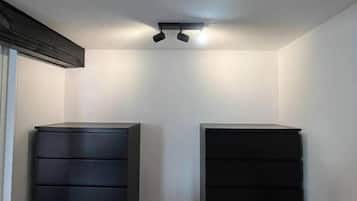 A room with a ceiling light fixture, two dark-colored dressers, and a wooden floor.
