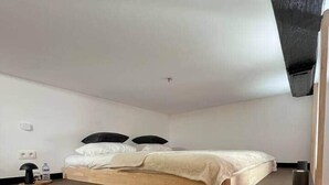 Une chambre à coucher avec un lit en bois, une petite table de chevet, une lampe et une prise électrique fixée au mur.