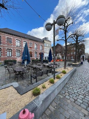 Een geplaveid straatje met terrasjes, een bakstenen gebouw en een lantaarnpaal.