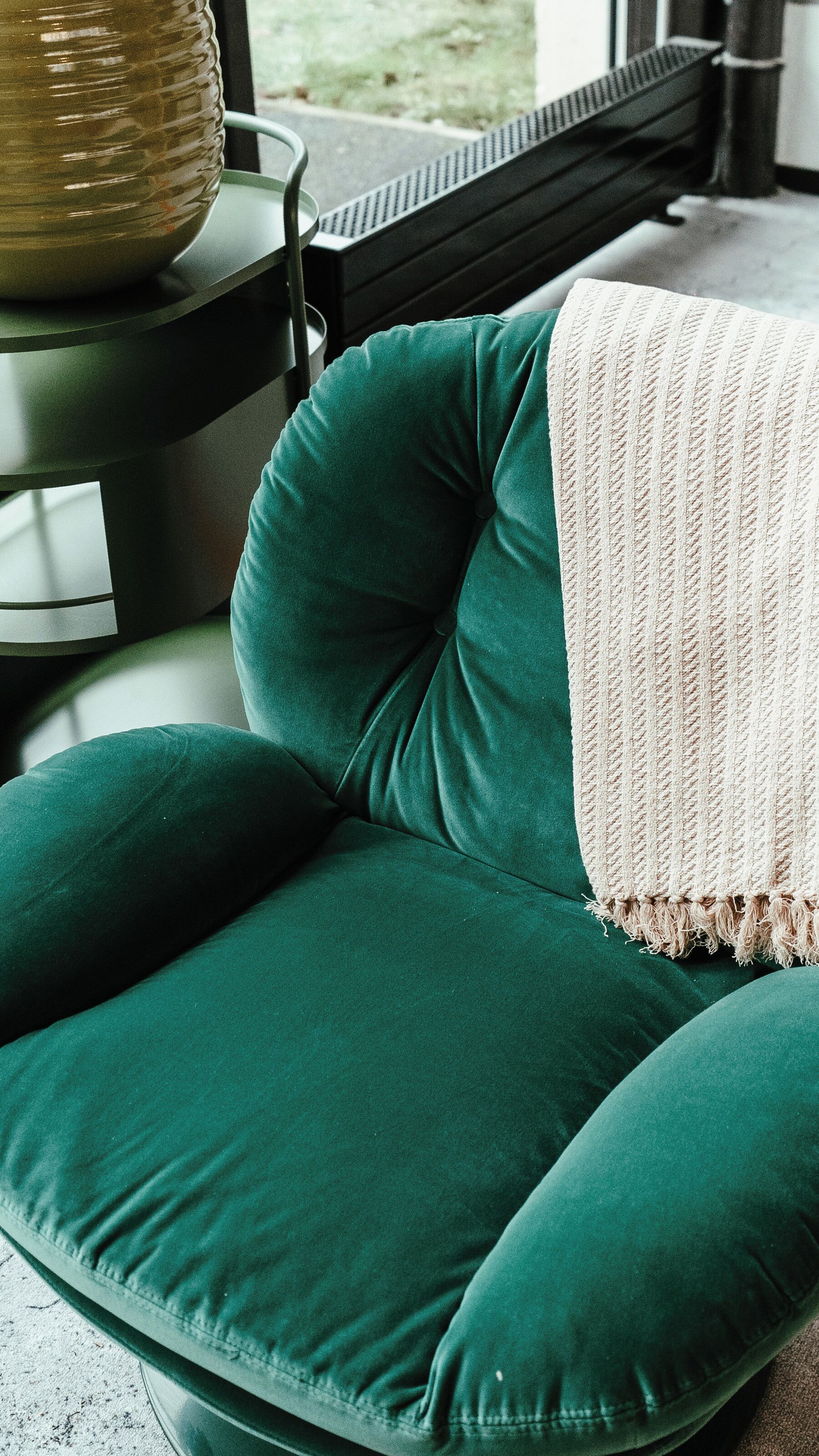 A green sofa with a textured throw blanket.