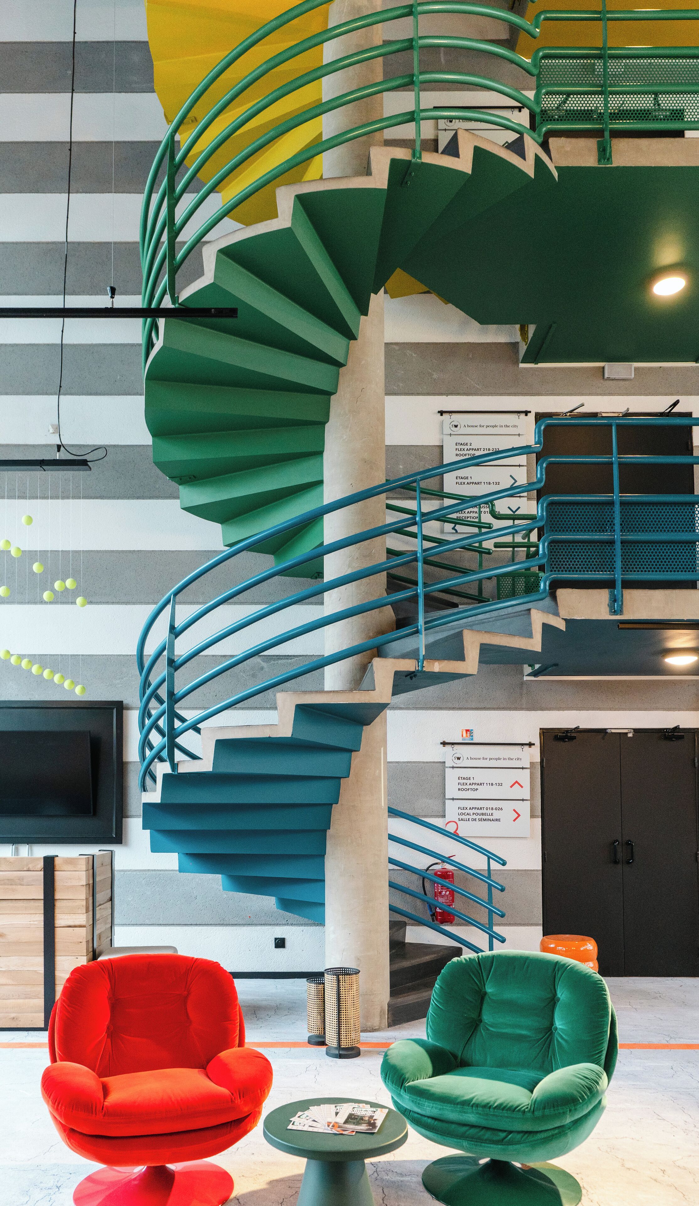 A modern interior with a spiral staircase, multiple seating areas, and directional signage.