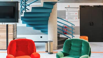Un interior moderno con una escalera en espiral, varias zonas de estar y señalización direccional.
