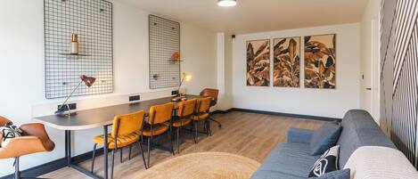 Una sala de estar moderna con un sofá grande, una mesa de comedor con sillas y obras de arte en las paredes.