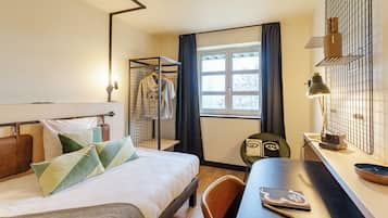 Une chambre d’hôtel comprenant un lit, un bureau, une chaise, une fenêtre et une armoire.