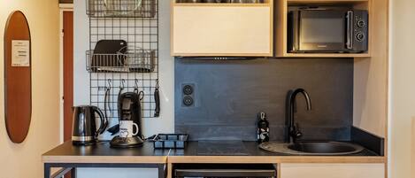 A compact kitchen with a microwave, coffee maker, and a dishwasher.