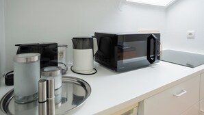 A kitchenette with a microwave, coffee maker, and stainless steel containers on a white countertop. - Guesthouse Elena Apartment 23 (Kassel)