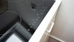 A modern kitchen with a black induction cooktop and a white oven. - Guesthouse Elena Apartment 23 (Kassel)