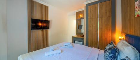 Una habitación de hotel con una cama, televisión, armario de madera y espejo.