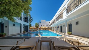 Un espace piscine avec des chaises longues et un ciel d’un bleu éclatant.
