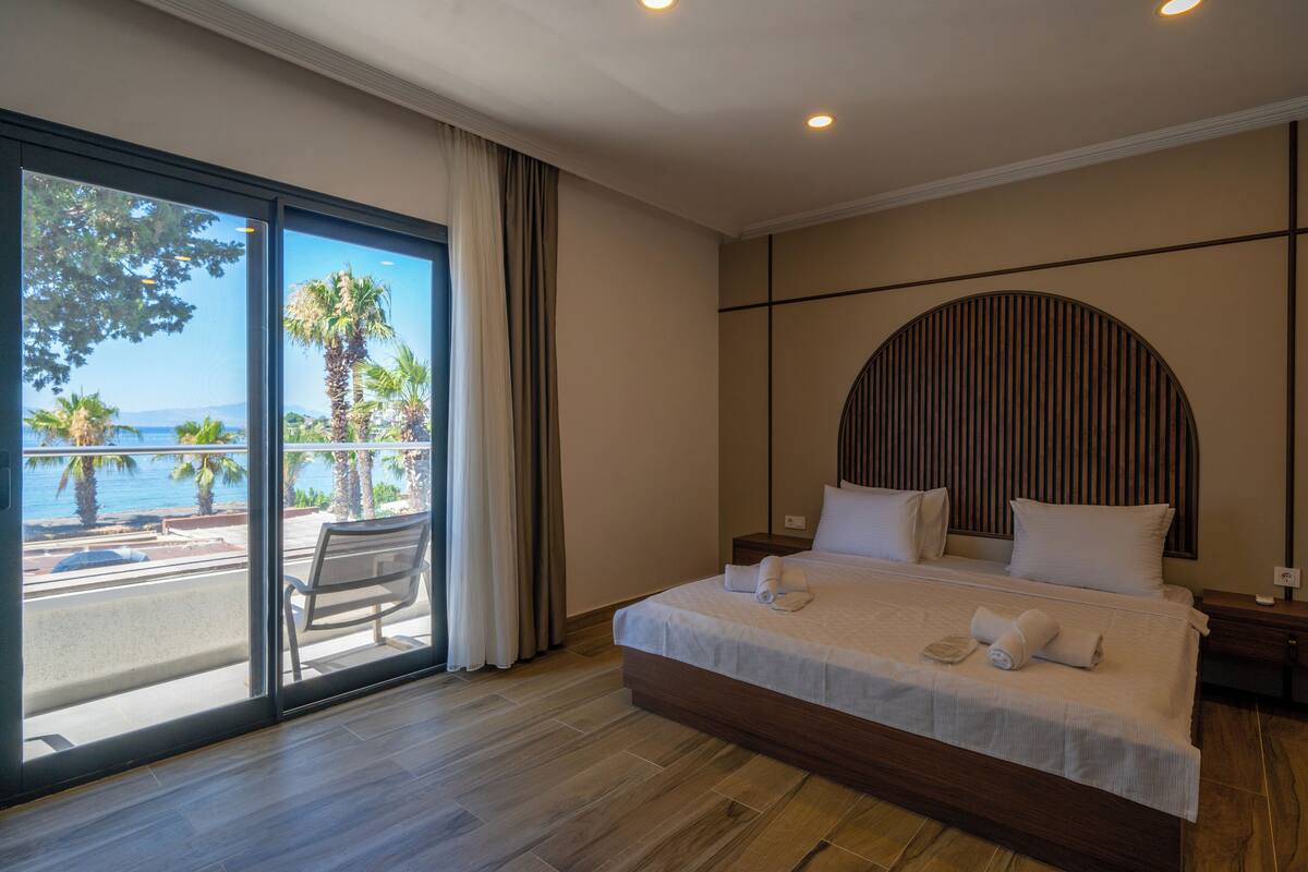 Une chambre d’hôtel avec un grand lit, une vue sur l’océan et un balcon équipé d’une chaise.