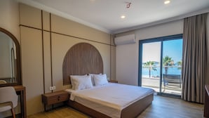 Une chambre d’hôtel moderne avec un grand lit, un bureau et une vue sur la plage.
